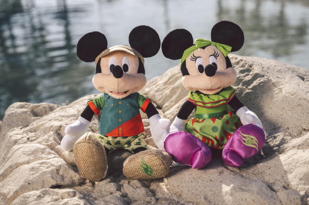 a couple of mickey mouse plush toys sitting on a rock
