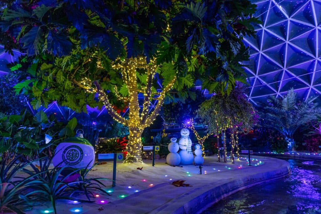 a tree with lights and snowmen in a garden